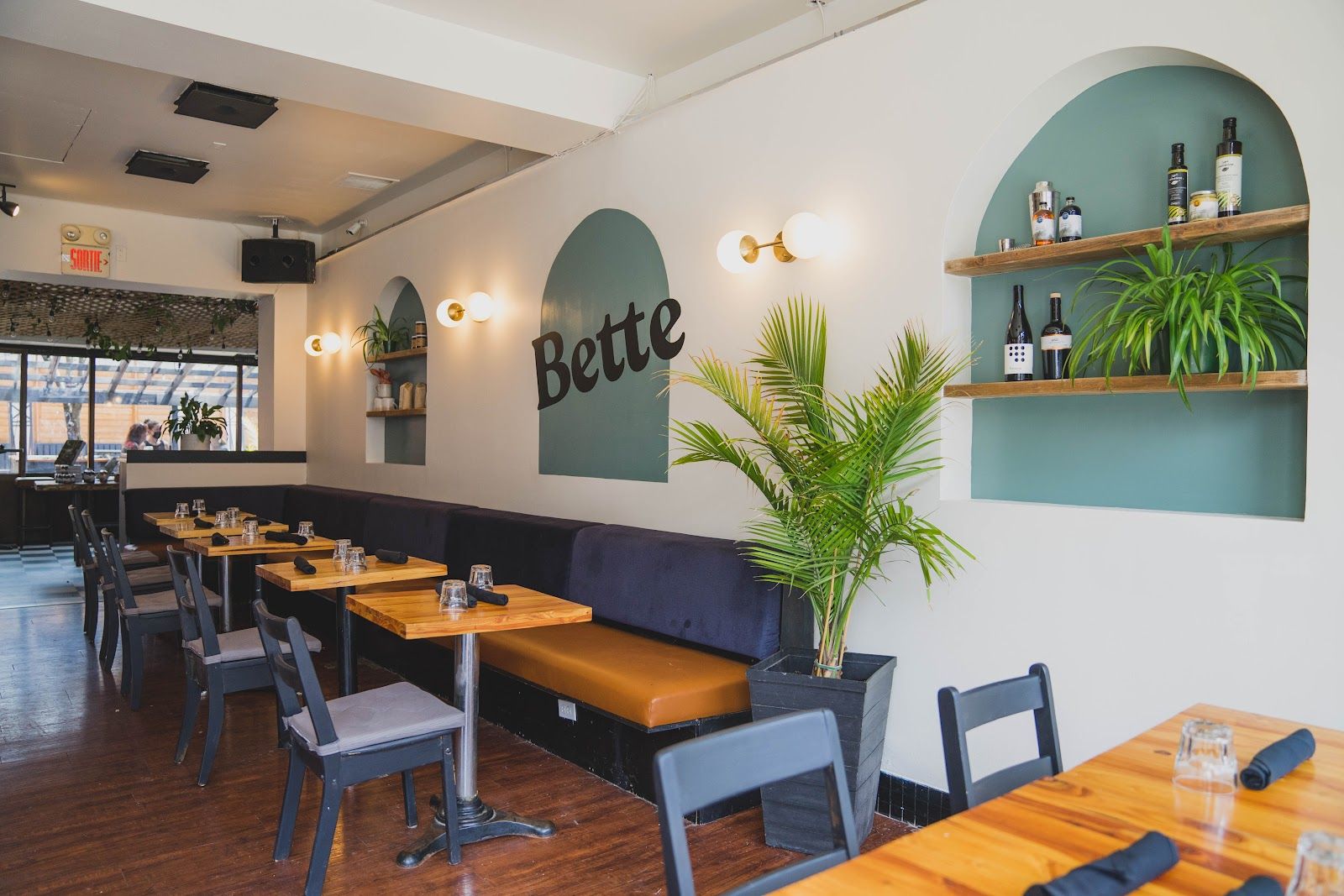 La salle du Bette : tables de bois, arches vert sauge, plantes et l'enseigne Bette