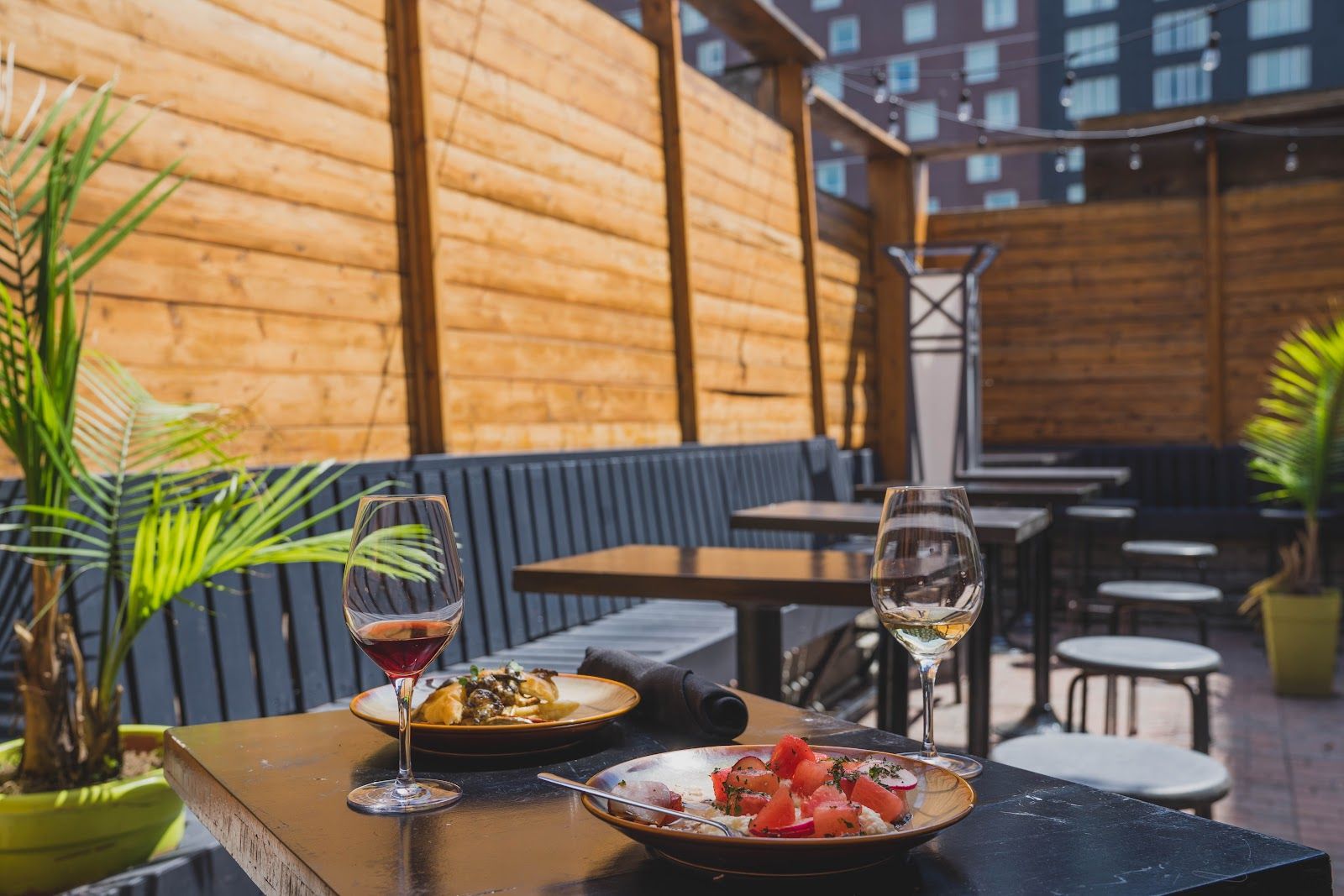 La terrasse du Bette : clôture de bois, plantes, tables dressées et verre de vin
